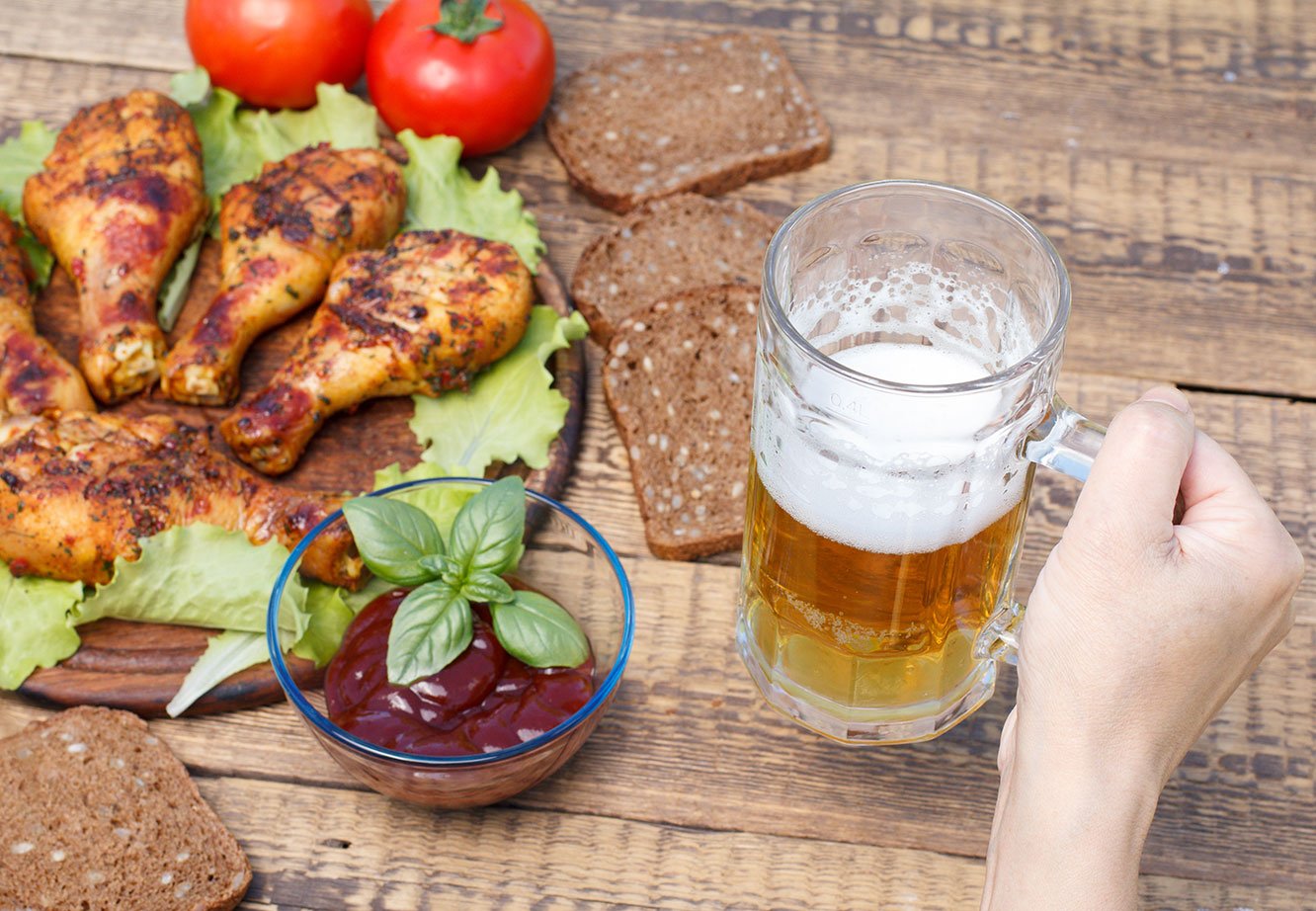 Female Hand Is Holding Glass Mug Of Beer With Grilled Chicken Le