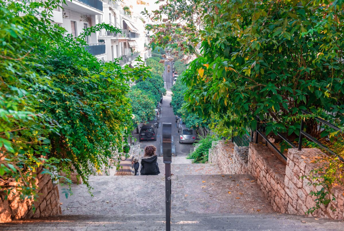 Rear view of a young boy and a young girl sitting side by side in the neighbourhood of Kolonaki, under mount Lycabettus